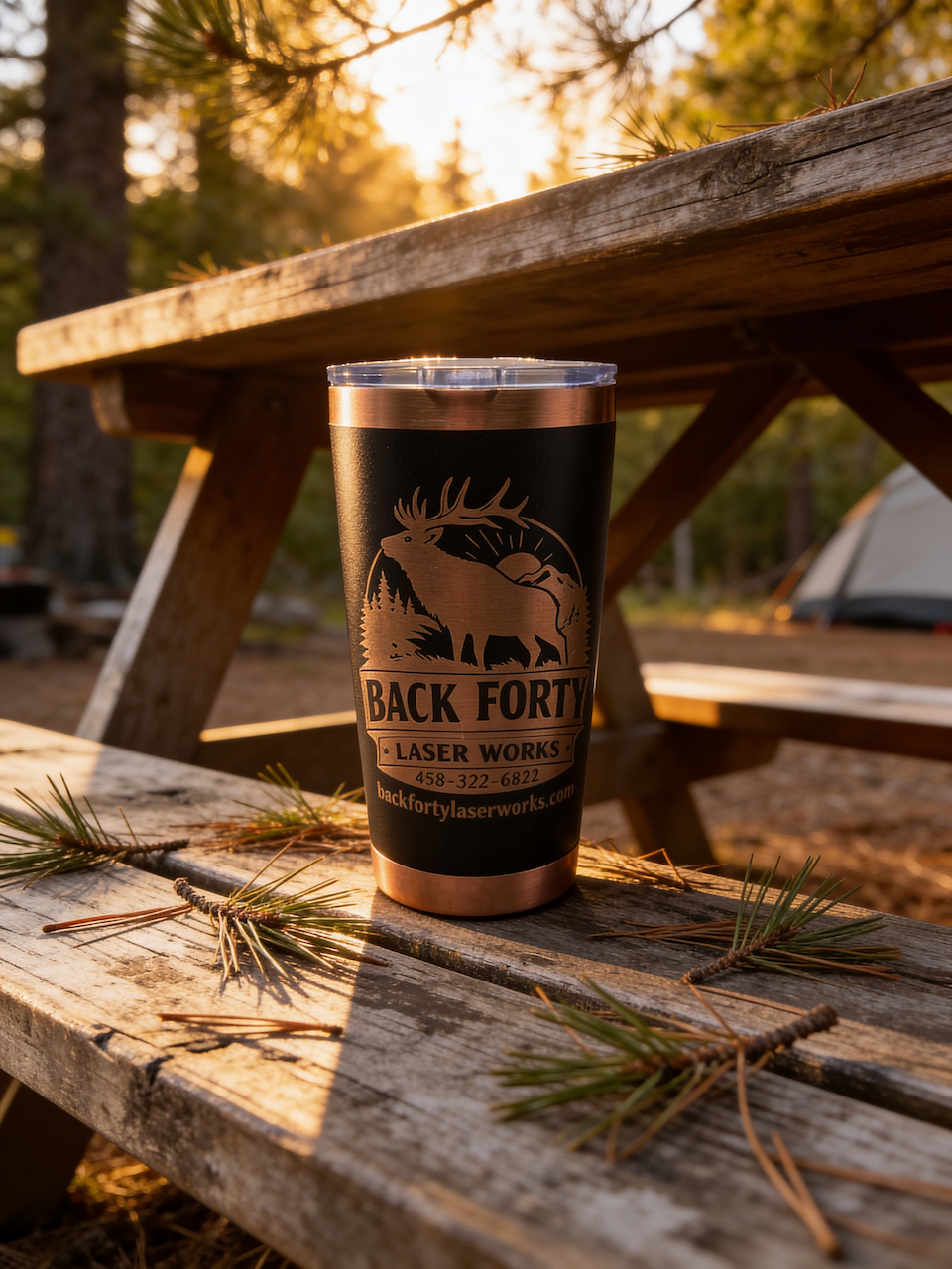 Custom engraved Back Forty Laser Works tumbler on a picnic table at sunset